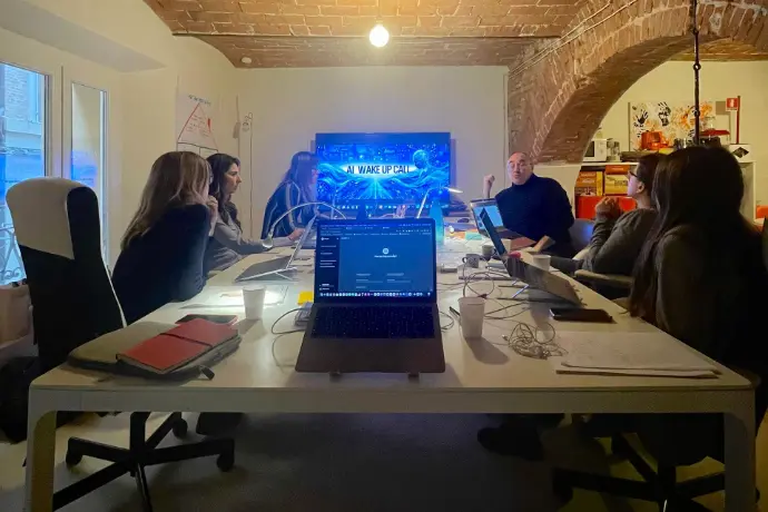Sergio Bertolini durante un seminario AI Wake Up Call in azienda, partecipanti attorno al tavolo riunioni